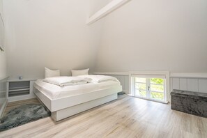 Une chambre à coucher avec un lit, une fenêtre et un plancher en bois.