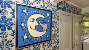 A framed artwork of a moon with a heart and stars on a wall with blue and white patterned tiles. - Kapitänshuis - Captain's house on Sylt with garden, terrace and comfortable (Sylt)