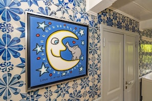 Una obra d'art amb un marc que mostra una lluna, un cor i estrelles a la paret, decorada amb rajoles blaves i blanques.