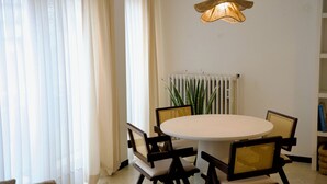 Comedor con una mesa redonda, cuatro sillas, un radiador y una lámpara colgante.