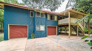 A two-story building with a red garage door, a balcony, and a covered outdoor area. - MiaCasa - by Lifestyle. Brunswick Heads (NEW BRIGHTON)