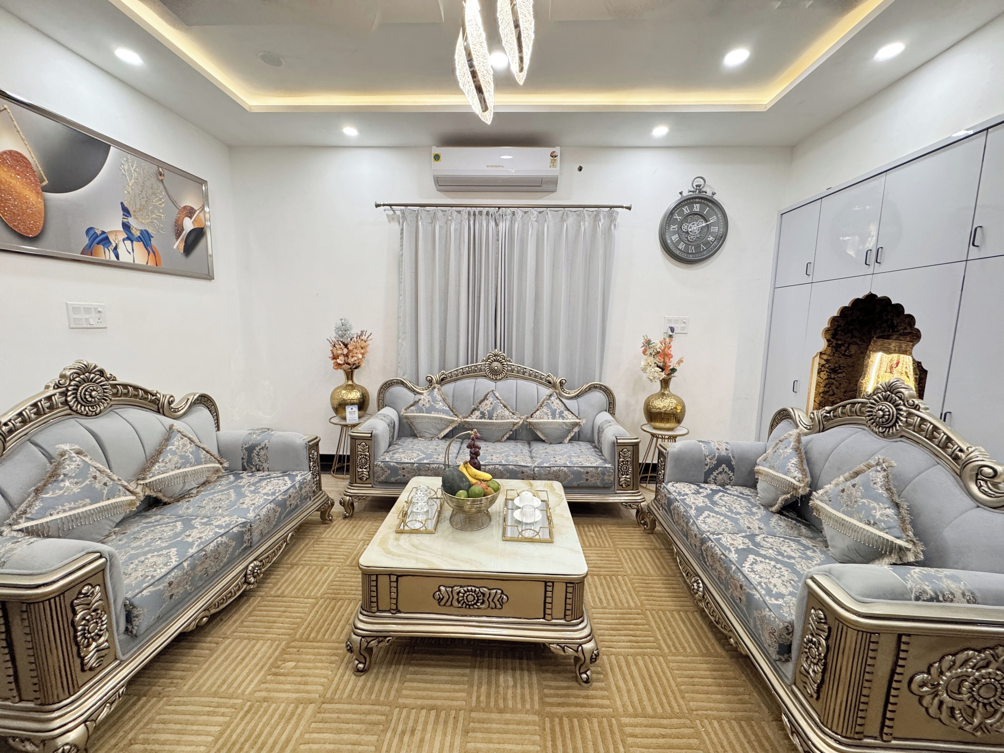 A living room with a sofa set, a coffee table, decorative vases, a clock, and an air conditioning unit.