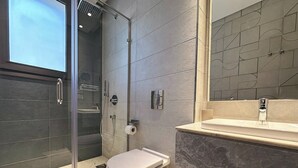 A modern bathroom with a glass-enclosed shower, a toilet, and a sink with a marble countertop. - Catalina Silver Palm New Cairo (cairo)