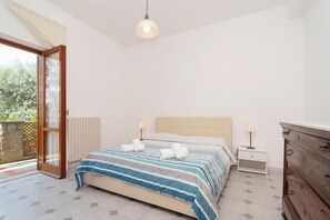 A bedroom with a bed, bedside tables, a dresser, and a sliding glass door leading to a balcony. - Limoneto - Giardino by Espresso Rentals (Campania)