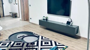 A modern living room with a TV, grey entertainment unit, and a patterned rug.
