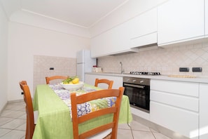 A compact kitchen with white cabinets, a stove, and a sink.