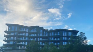 Un edificio de varios pisos con balcones y ventanas amplias, rodeado de árboles.