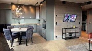Una cocina moderna con armarios grises, una mesa de comedor con sillas y un televisor montado en la pared.