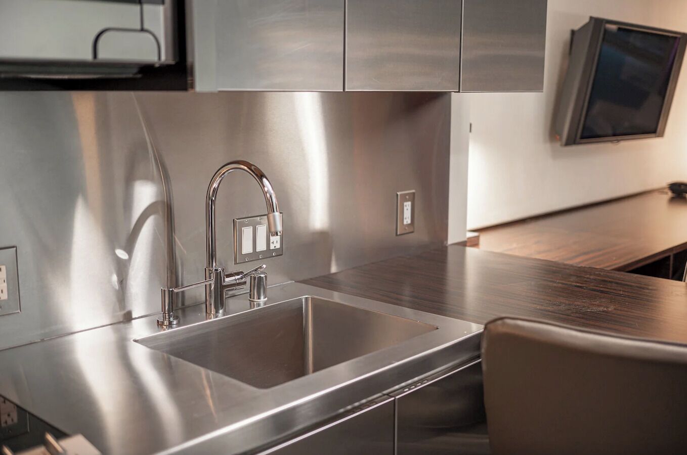 A modern kitchen with stainless steel appliances, a double sink, and a wooden countertop.
