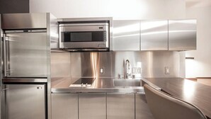 Una cocina moderna con electrodomésticos de acero inoxidable, un microondas integrado y un lavamanos.