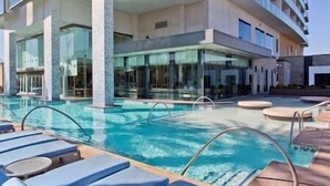 A swimming pool with lounge chairs, a glass-enclosed building, and a clear sky. - Palms Luxury Strip View 1BD/1.5BA Open Balcony#22KA (Las Vegas)