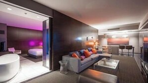 A modern hotel room with a large sofa, a dining area, and a separate living space. - Palms Luxury Strip View 1BD/1.5BA Open Balcony#29KA (Las Vegas)