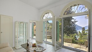 A spacious room with a large sliding glass door leading to a balcony with a mountain view. - Romantic Terrace With Lake View (Lugano)