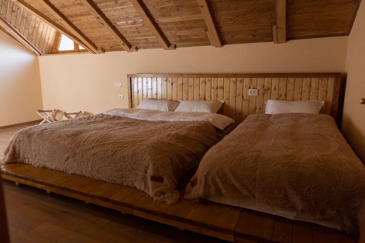 Ein Schlafzimmer mit zwei Betten, einem Holzkopfende und einer schrägen Decke.