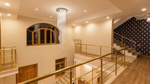 Un interior de varios niveles con una escalera, piso de madera y un candelabro.