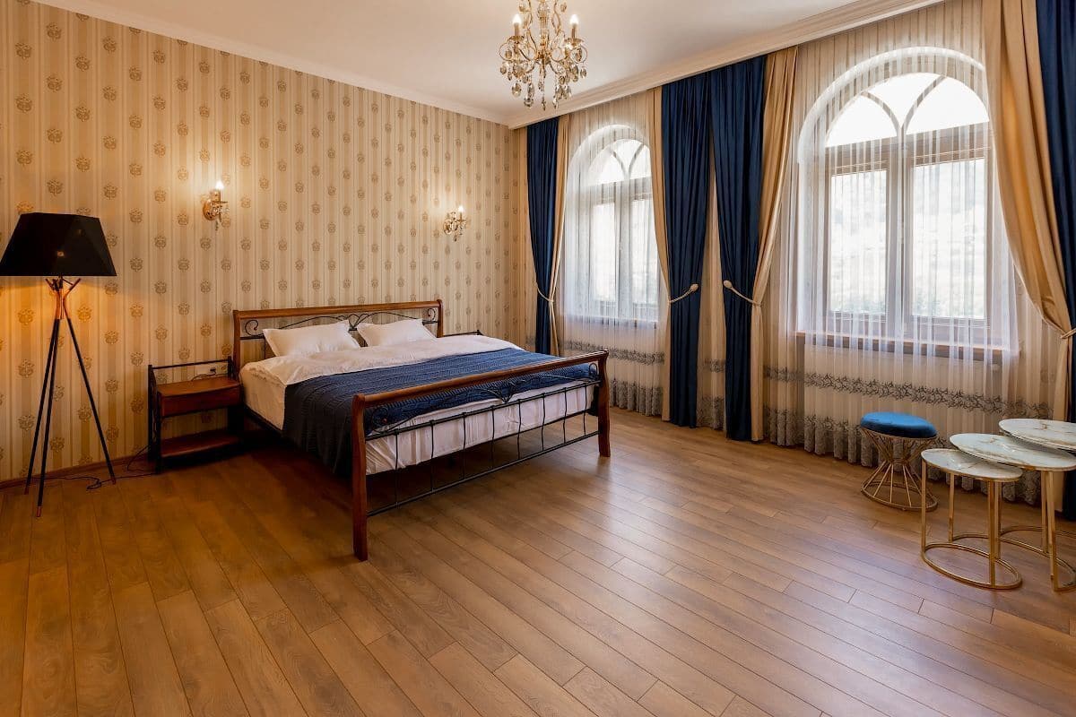 Ein ordentlich eingerichtetes Schlafzimmer mit einem hölzernen Bett, einer Stehlampe und zwei kleinen Tischen.