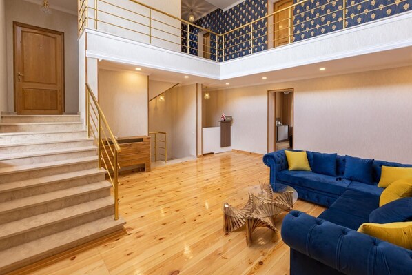 Un vaste espace de vie comprenant un escalier, un canapé bleu et un plancher en bois.