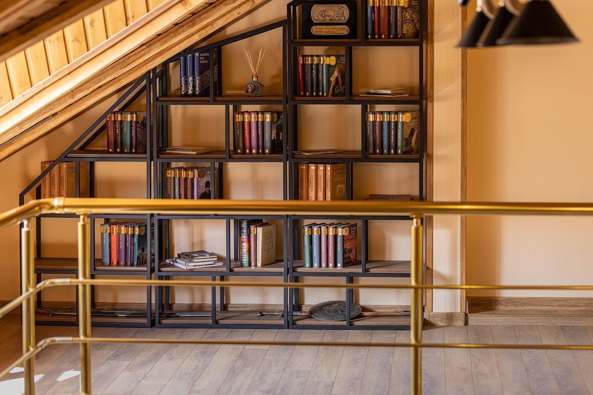 A multi-level wooden staircase with a black metal railing, leading to a bookshelf filled with books and decorative items.