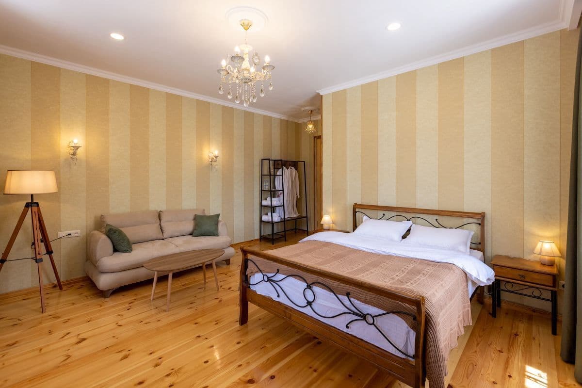 Ein Schlafzimmer mit einem hölzernen Bett, einer Schlafcouch, einer Stehlampe und einem Kronleuchter.