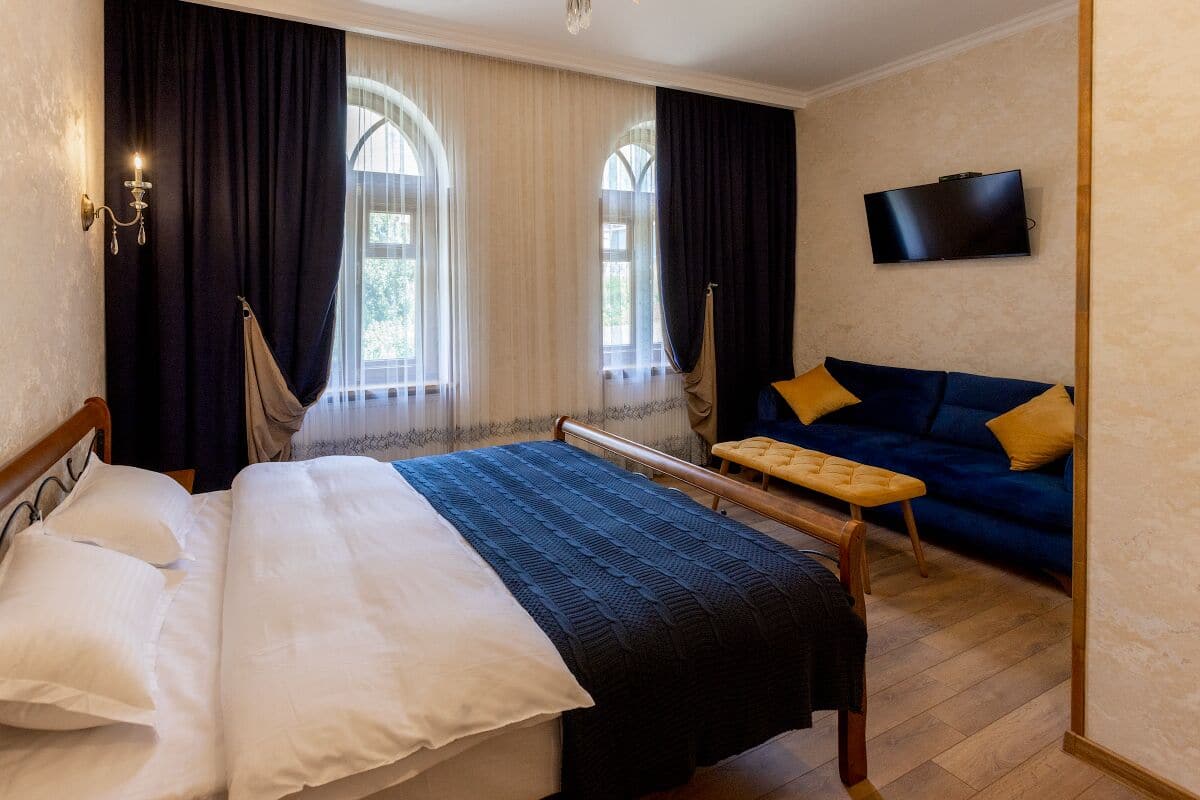 Ein Schlafzimmer mit Bett, einer Bank, einem Sofa und einem Fernseher.