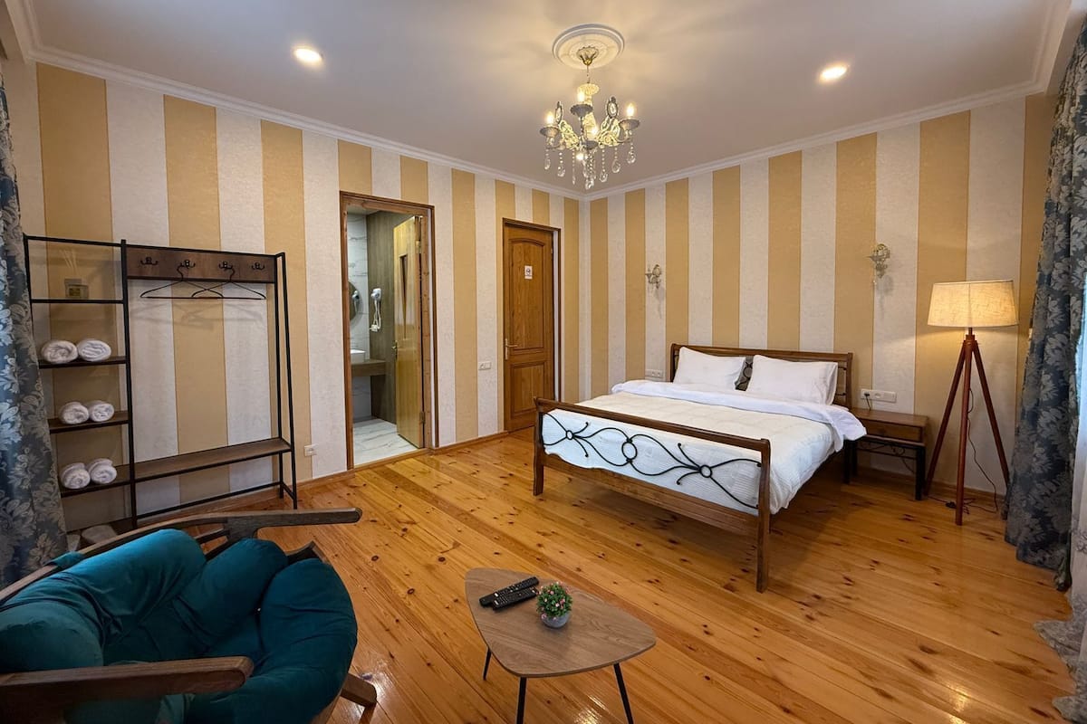 Ein Hotelzimmer mit Bett, Stuhl, Tisch, Lampe, Kleiderschrank und Duschbereich.