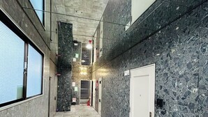 Un couloir doté d’un sol en marbre, d’un extincteur et d’une porte au fond.