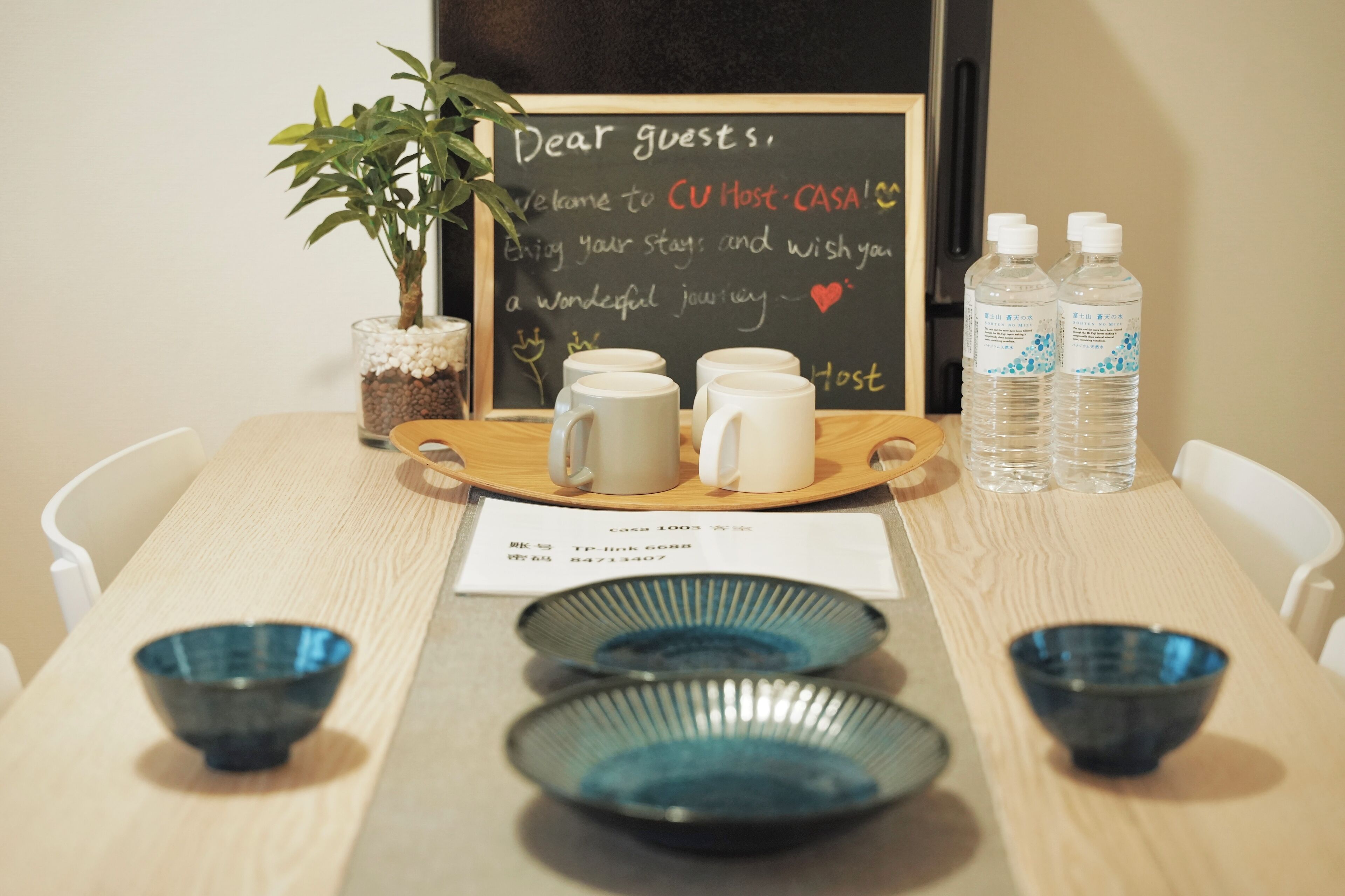 A table with a chalkboard greeting, two water bottles, and three bowls.