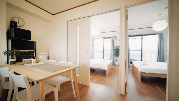 Une chambre d’hôtel moderne avec un plancher en bois, un coin repas comprenant une table et des chaises, un lit et une grande fenêtre.