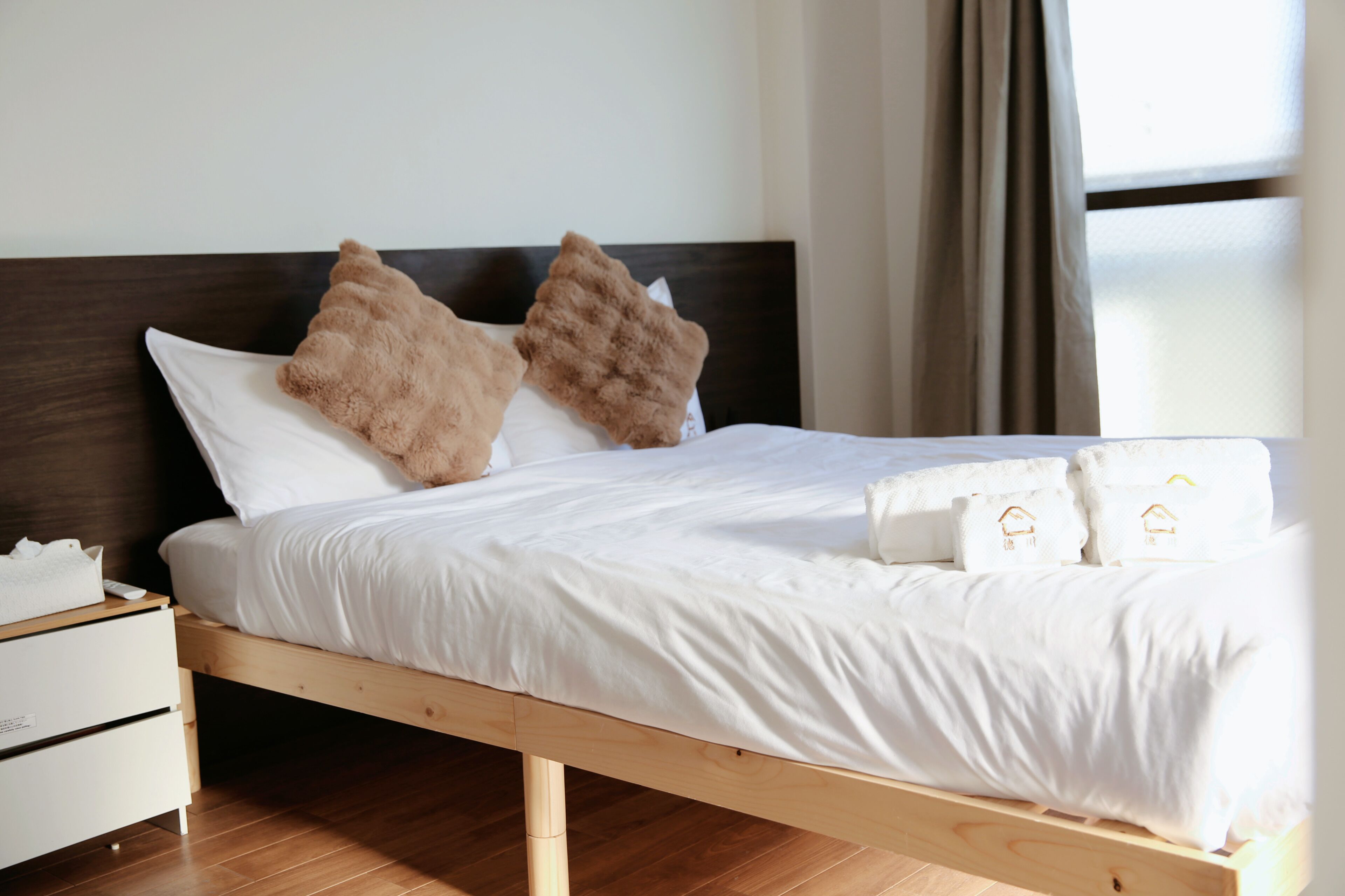 A bed with white bedding, two brown pillows, and a wooden headboard.