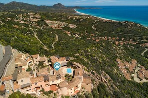 An aerial view of a coastal village with terraced houses, a beach, and a clear blue sea. - Cliffside Blue - Costa Rei (Muravera)