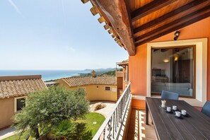 Un balcon avec une table préparée pour le thé, offrant une vue sur un paysage côtier.