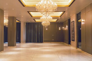 A spacious lobby with a large chandelier, recessed lighting, and a modern design.