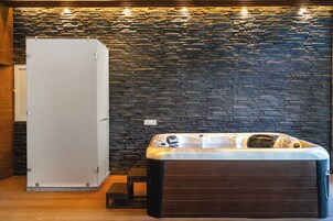 A spa room with a stone wall, a hot tub, and a white cabinet.