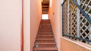 Un escalier menant à un niveau supérieur, bordé d’un mur et d’une clôture en treillis de bois.