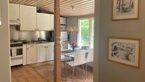 Una cucina con mobili bianchi, un fornello e un'area pranzo con tavolo e sedie.