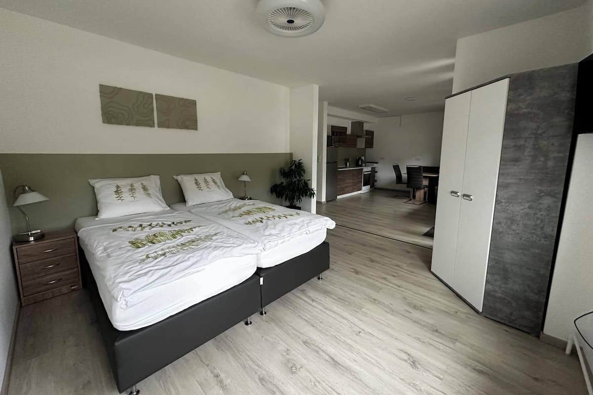Egy modern hálószoba, amelyben franciaágy, éjjeliszekrények, íróasztal és gardrób található.