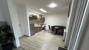 A modern kitchen with wooden cabinets, a refrigerator, and a dining area with a table and chairs. - Haus Wijnen (Bad Bentheim)