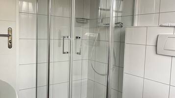 A modern bathroom with a glass-enclosed shower, a toilet, and a sink.