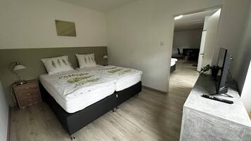 A modern bedroom with a bed, bedside tables, a desk, and a TV.