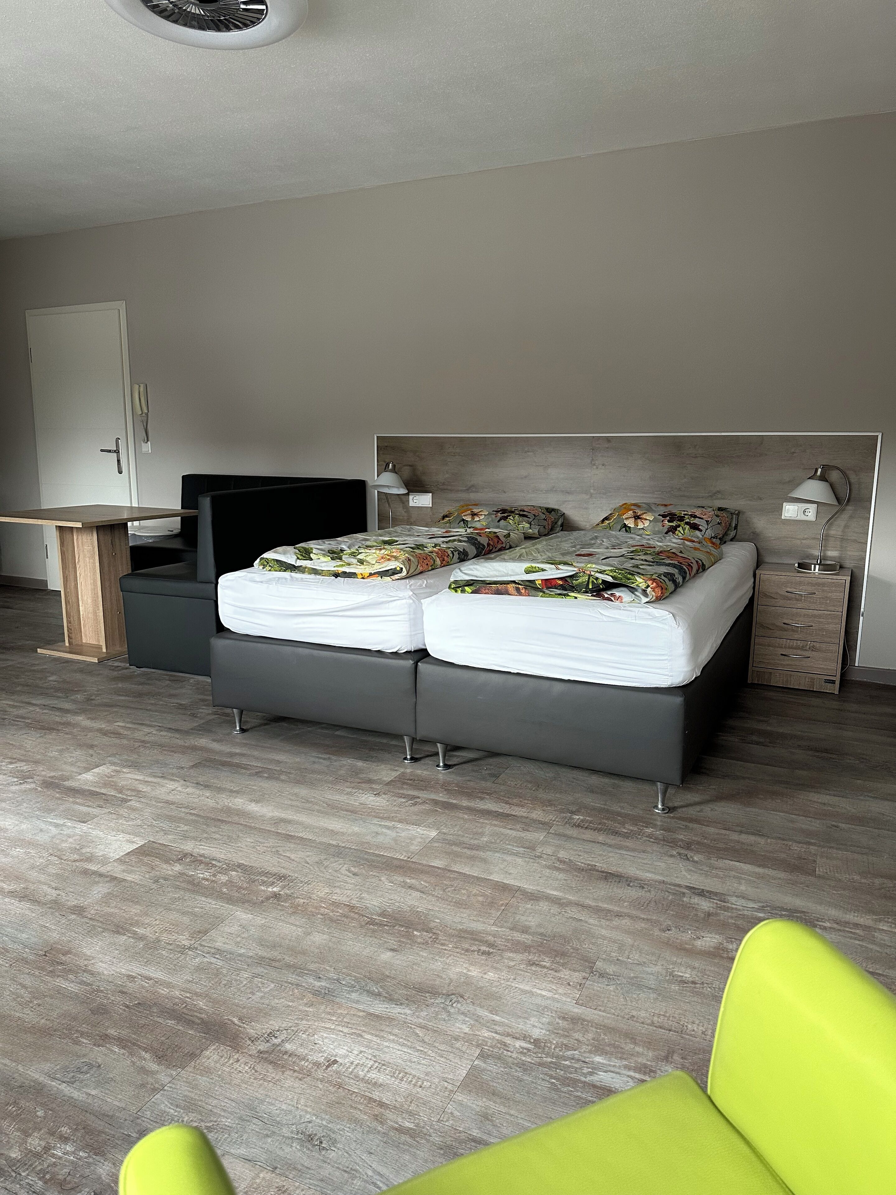 A modern bedroom with a large bed, bedside tables, and a desk.