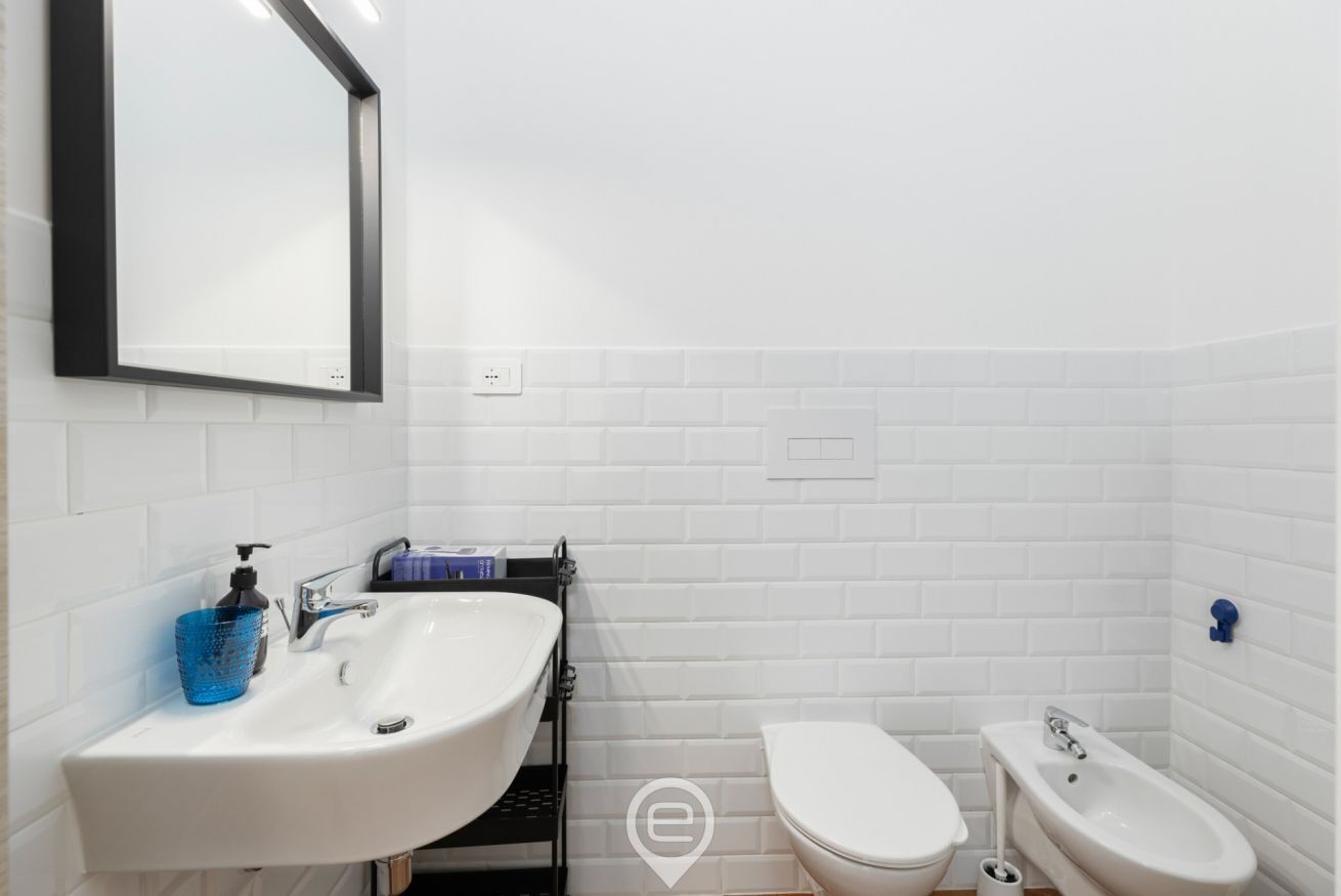 A bathroom with a white sink, a toilet, and a bidet.