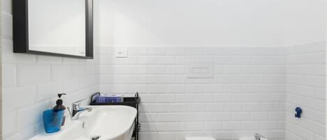 A bathroom with a white sink, a toilet, and a bidet.