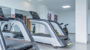 Tres cintes d'entrenament a una sala de fitness amb parets blanques i un sòl net.