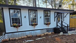 Un petit bâtiment d’un seul étage, doté de trois fenêtres, chacune ornée d’un pot de fleurs suspendu.