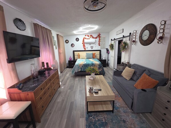 A modern bedroom with a bed, a sofa, a TV, and a desk.