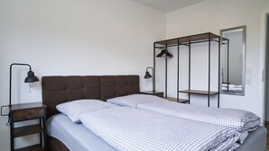 Ein Schlafzimmer mit einem Bett, zwei Nachttischen, einem Hängebrett und einem Spiegel.