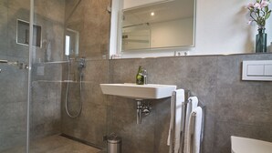 A modern bathroom with a glass-enclosed shower, a white sink, and a toilet. - Vacation apartment Squirrel (Günzburg)