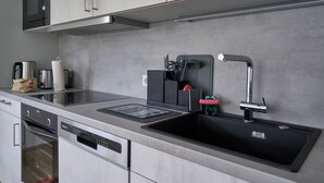 A modern kitchen with stainless steel appliances, a dishwasher, and a sink with a faucet. - Vacation apartment Squirrel (Günzburg)