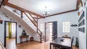 A spacious dining area with a wooden table and chairs, a staircase with wooden railings, and a view of the outside through a window. - Holiday Home La Perla (La Puebla de Cazalla)