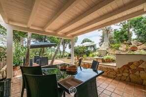 An outdoor patio with a glass-top table, wicker chairs, and potted plants.